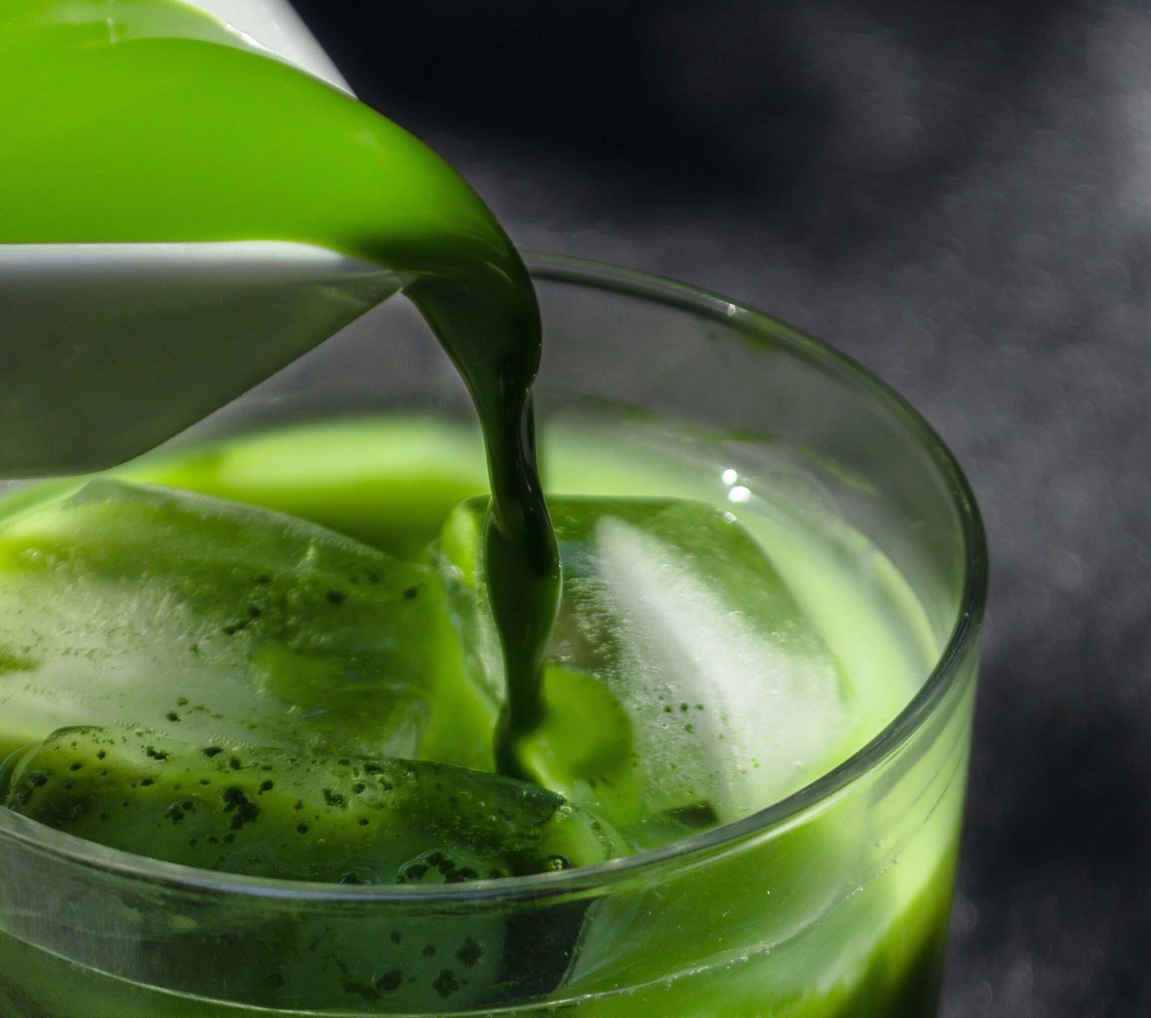 Iced matcha latte being poured into a glass—vibrant green tea rich in antioxidants, L-theanine, and natural energy support.