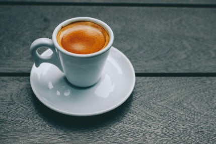 a cup of mushroom coffee that looks like espresso nicely set on a wooden table with moody lighting