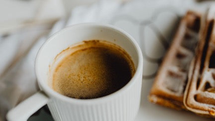A steaming cup of mushroom coffee in a white mug