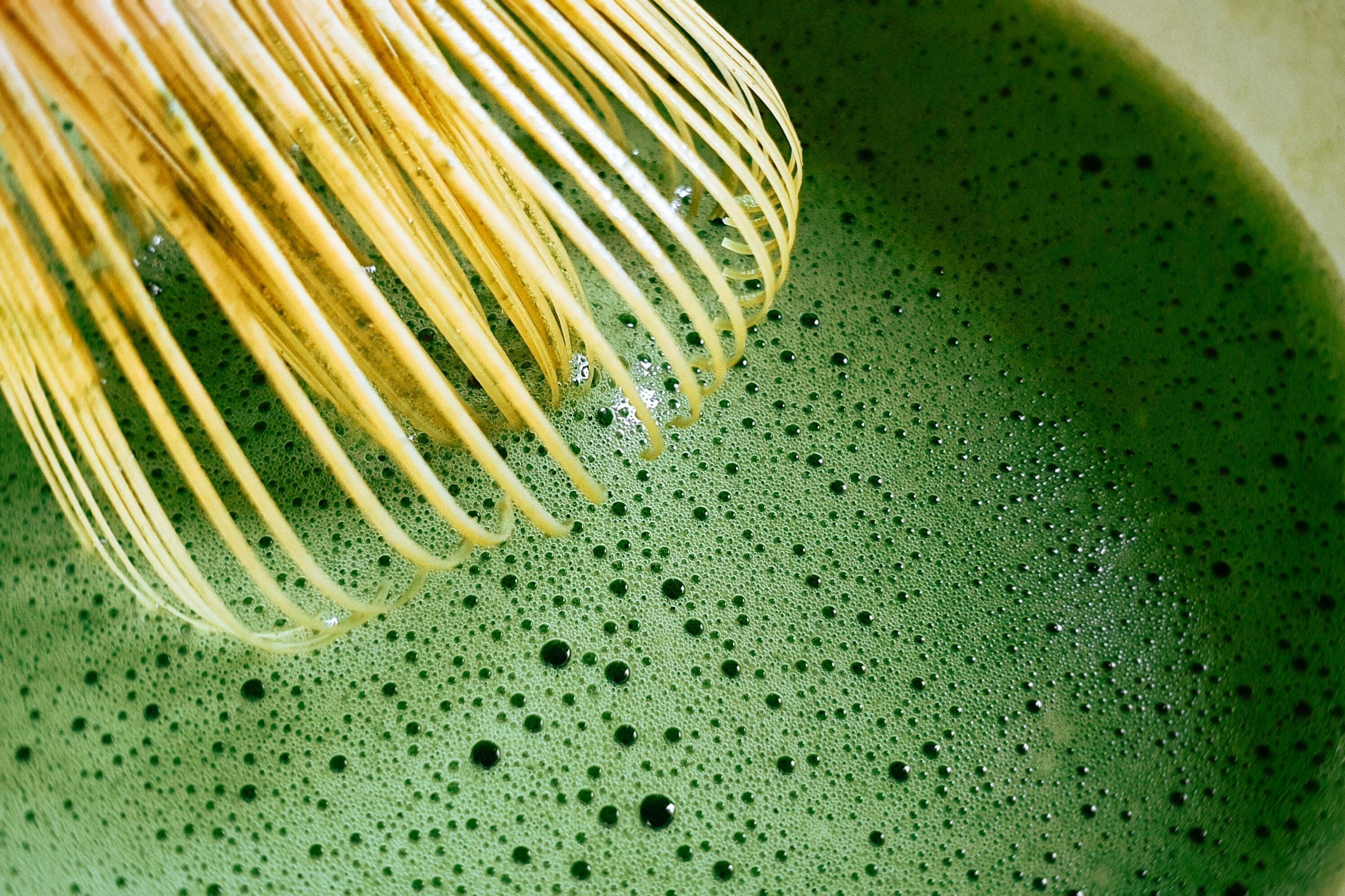 Ceremonial-grade matcha being whisked with a bamboo chasen into a smooth, frothy green tea—rich in antioxidants and L-theanine.