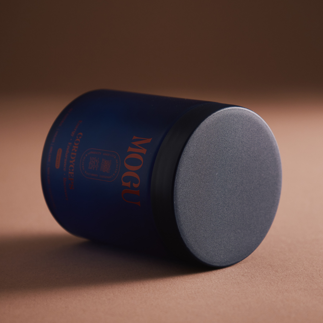 Cordyceps capsules in a blue cylindrical container with gray lid on a brown background