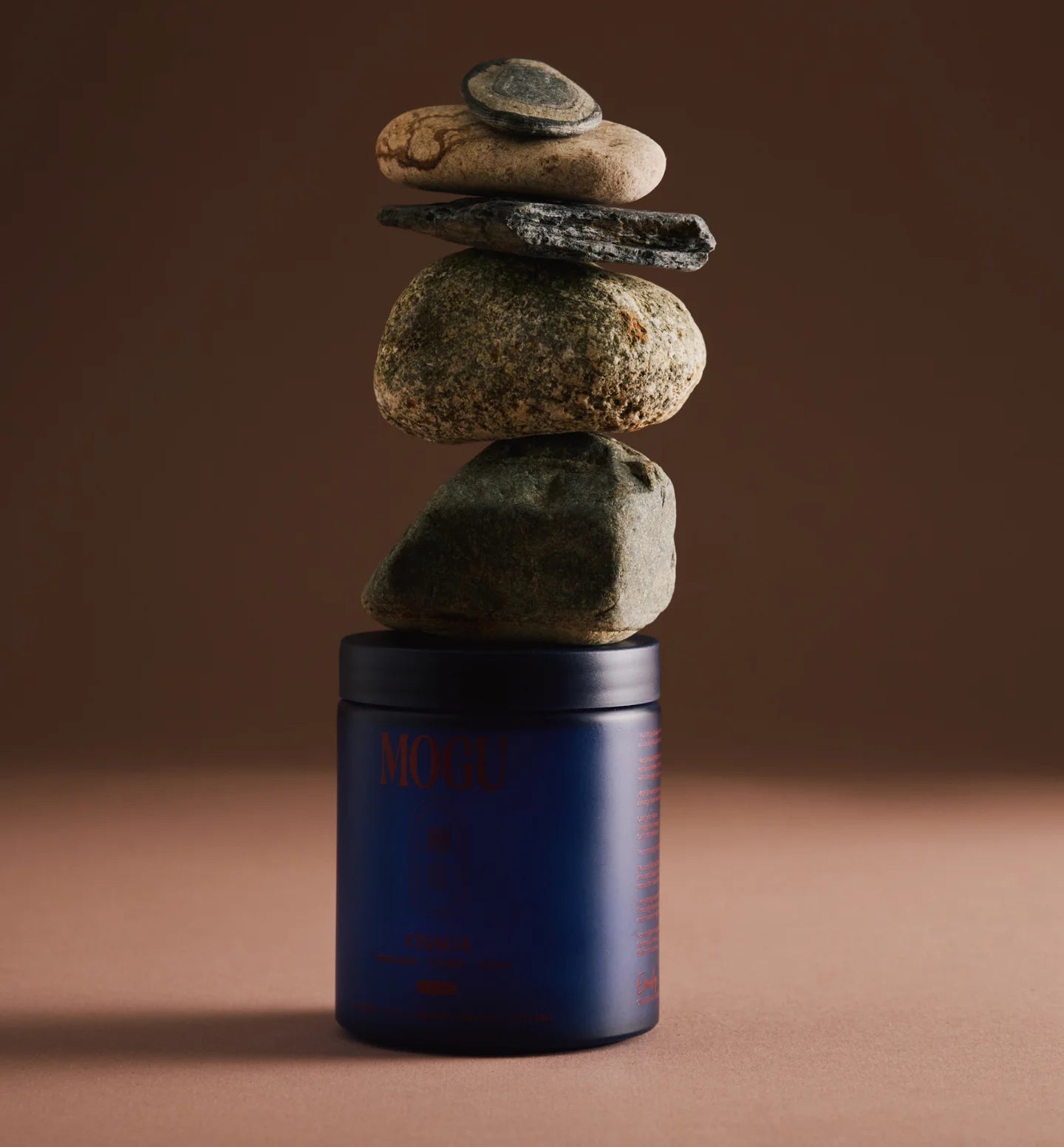 Organic Chaga capsules in a blue container with stacked stones on a brown background